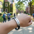 A black bracelet with a silver engraved plate, featuring the word "Graduation," worn on a person's wrist outdoors.