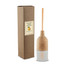 A wooden reed diffuser with a cylindrical base and two reeds, packaged in a brown box. The diffuser has a light colour.