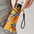 A small, multi-coloured umbrella with a patterned design, being held and inserted into a pocket.