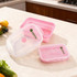A set of pink collapsible silicone food storage containers in various sizes with a logo on the side, displayed on a kitchen countertop.