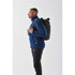 A man wearing a blue fleece jacket carries a black Sargasso backpack on his back. The backpack has a simple design and logo.