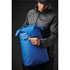 A blue backpack with a zippered pocket being held by a person in a black jacket and cap. Features a logo.