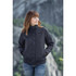 A woman wearing a black polar HD 3-in-1 jacket outdoors, with mountains in the background. The jacket has a logo.
