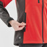 A red and black women's softshell jacket featuring zippered pockets and a logo on the lower side.
