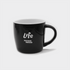 A black ceramic mug with a curved design and a handle, featuring a logo on the front.