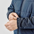 A navy blue puffer jacket featuring elastic cuffs, shown with hands adjusting the sleeve. The jacket has a logo.