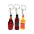 Three colourful resin keychains shaped like drink bottles, featuring red, amber, and black designs with keyring attachments.