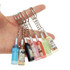 A hand holding multiple custom-shaped resin keychains in various colours resembling miniature bottles.