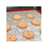 A silicone baking mat with a red border and circular markings, featuring freshly piped pastry swirls.