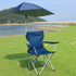 A navy blue adjustable umbrella attached to a folding camping chair by a universal clamp, set by a lake.