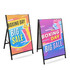 Two metal A-frame signs with vibrant designs featuring bright colours, advertising a Boxing Day sale. Each sign has a logo.