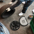 A black car wheel tool kit with various tools, placed beside a person holding a tyre in a workshop setting.
