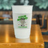 A stack of white PLA double wall compostable paper cups with a colourful sleeve and branding on a wooden table.