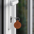 A round brown PU leather keyring attached to a silver key in a door lock.