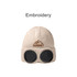 A beige beanie with black goggles attached and an embroidered logo featuring mountains.
