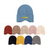 A collection of earflap beanies in blue, red, beige, pink, cream, black, yellow, and grey, with a logo on one.