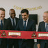 A red ribbon marked "BOXING" with a logo, held by four men in suits, in a setting with a "Congratulations" banner.