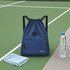 A navy blue drawstring backpack with a front pocket, next to a drink bottle and a towel on a green surface.