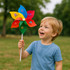 A child smiles while holding a six-leaf pinwheel featuring red, blue, yellow, and green petals with various logos.