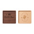A square wooden coaster featuring a dark wood and a light wood side, each with unique engravings, including a logo.