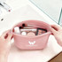 A pink silicone cosmetic bag with various beauty products and tools inside, featuring a logo on the front.