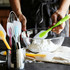 A green silicone spatula is held above a glass mixing bowl filled with flour, surrounded by various utensils.