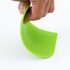 A green plastic flexible bowl scraper held by a hand, showcasing its bendable design.