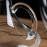 A clear glass decanter featuring a unique handle design, resting on a wooden surface.