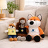 Three plush dolls displayed on a sofa: a small fox in yellow, an emu in grey, and a large orange fox, all wearing black tank tops.