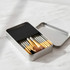 A metal box set containing 12 brushes with silver and gold accents, nestled in a sleek container.
