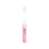 A transparent pink foldable handle toothbrush with a white bristle head, encased in a matching transparent holder.