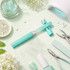 A gradient glass nail file in turquoise, surrounded by nail care tools, glitter, and decorative elements on a pale green background.