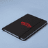 A black A5 notebook with a logo on the cover and an elastic closure, set against a light blue background.