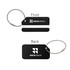 A square aluminium luggage tag in black with a silver wire attachment, featuring a logo on both sides.