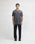 A unisex heavyweight cotton t-shirt in grey, paired with light blue jeans and black sneakers, featuring a logo.