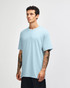 A light blue heavyweight cotton unisex t-shirt on a model, featuring a simple design and a logo.