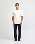 A model wearing a lightweight off-white unisex t-shirt paired with blue jeans and white sneakers, featuring a logo.