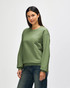 A man wearing a green crewneck sweatshirt, featuring long sleeves and a relaxed fit. The sweatshirt has a logo.