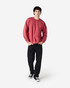 A man wearing a red Gildan Heavy Blend adult crewneck sweatshirt and black jeans, with a logo on the sweatshirt.