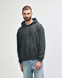 A grey Gildan Heavy Blend adult hooded sweatshirt displayed on a model, featuring a front pocket and a hood.