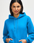 A blue Gildan Heavy Blend adult hooded sweatshirt worn by a female model, featuring a hood and drawstring.