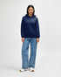 A navy blue Gildan Heavy Blend adult hooded sweatshirt worn by a model with jeans and sneakers. The sweatshirt features a hood and pockets.