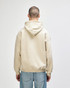 A beige hooded sweatshirt with a back view, featuring a hood and casual fit. The model wears blue jeans.