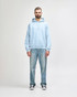 A light blue Gildan Heavy Blend adult hooded sweatshirt paired with denim jeans and white sneakers.