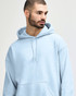 A blue hooded sweatshirt with a front pocket, worn by a young woman with long hair. It features a logo on the garment.