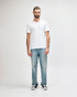 A white Gildan Softstyle adult V-neck T-shirt on a male model, paired with dark denim jeans. The shirt has a logo.