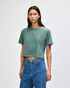 A green boxy t-shirt featuring a crew neck and short sleeves, styled with high-waisted jeans.