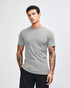 A grey unisex short sleeve T-shirt displayed on a model with hands in pockets, featuring a simple design.