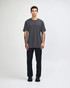 A unisex fine jersey short sleeve t-shirt in black, worn with beige pants and blue sneakers, with a logo visible.
