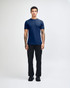 A model wearing a navy unisex fine jersey short sleeve t-shirt and tan wide-leg pants. The t-shirt has a logo.